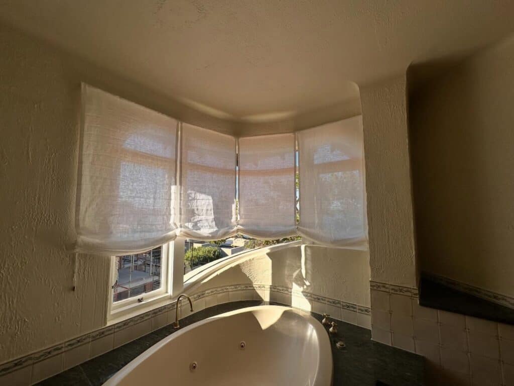 lowered relaxed roman blinds on curved window in Perth