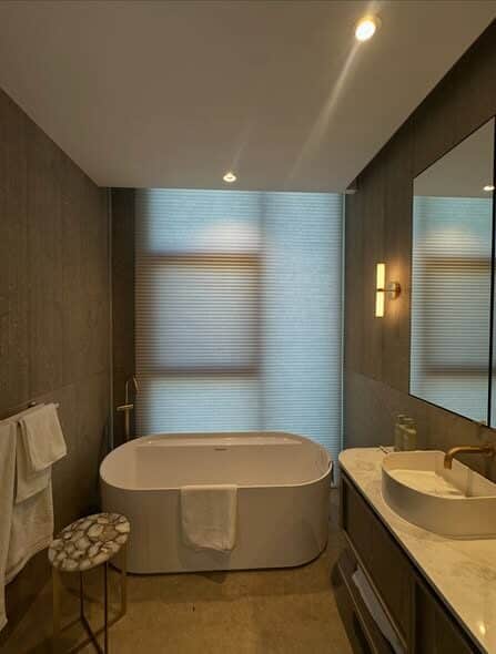 Cellular honeycomb blind filtering daylight behind a freestanding bath in a contemporary Perth bathroom