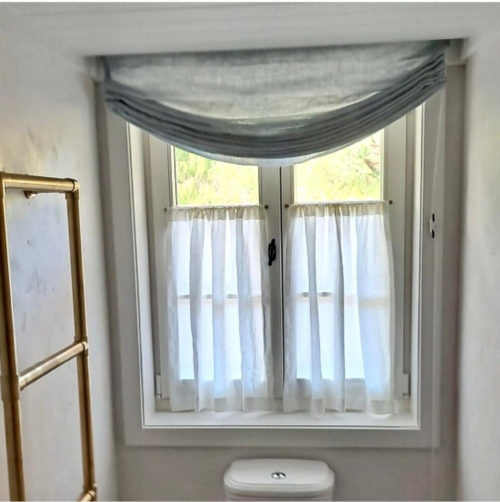 Linen café curtains covering the lower half of a WC window with a soft swag above, giving privacy while keeping the light.