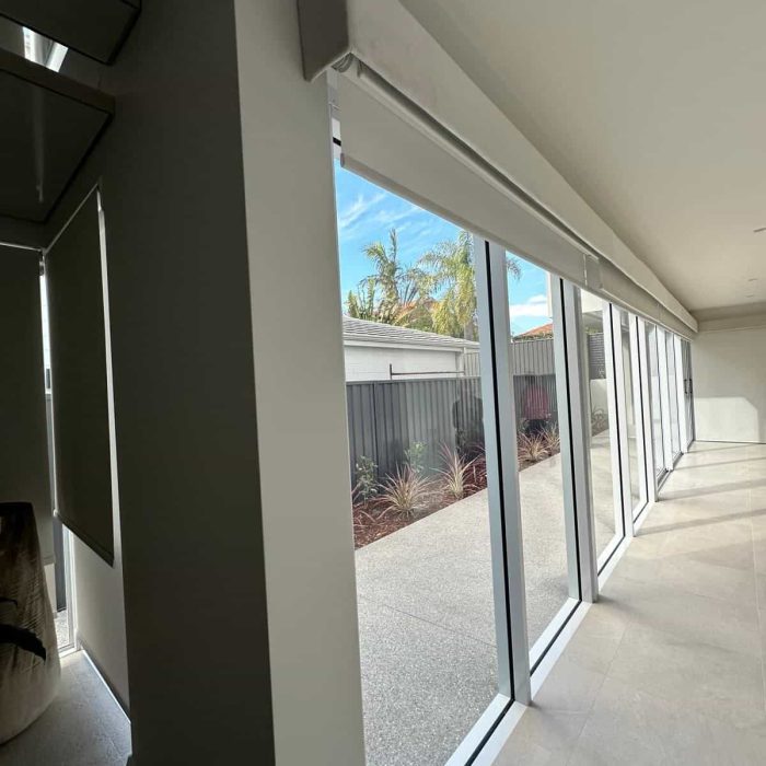 Double roller blind fitted beneath a boxed pelmet along a floor-to-ceiling window